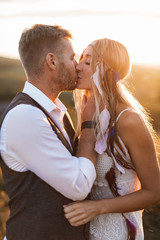 Close up portrait of handsome blond man and pretty woman in stylish boho rustic clothes, kissing. Lovely couple in eco boho rustic style, standing in summer field. Kissing sensual moment © sofiko14