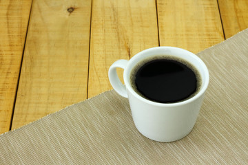 Black coffee or Americano, a white coffee cup on cream colour plate mat with on table top