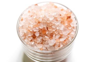 Himalayan pink salt in crystals on glass bowl isolated on white background.