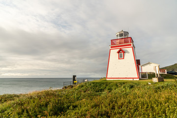 Red and white square wooden tower lighthouse on a bluff above the north atlantic ocean, Fox Point,...
