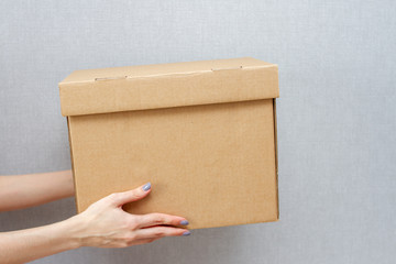 Woman holds out her hands with a cardboard box. The courier delivered the parcel.