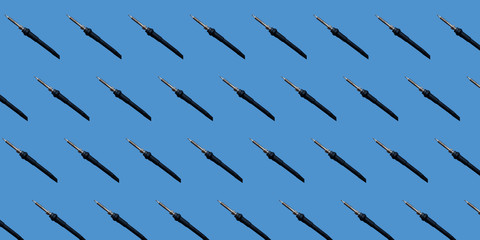 Seamless repeating soldering iron pattern. The black soldering iron has no wire. They are depicted on a blue monophonic background. Template for packaging.