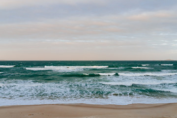 Fototapeta na wymiar Empty long beach with a beautiful sea view. White foam from a sea wave