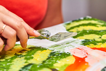 Artist paints landscape in gouache using a using a putty knife. Woman's hand is holding brush....