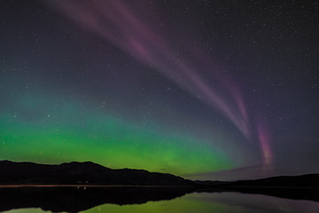 Aurora Borealis Northern Lights seen outside of Whitehorse, Yukon Territory Canada during fall, autumn with bright green band seen along river with reflection in water below. Wallpaper, desktop
