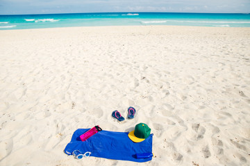 vacation and summer holidays concept - flip flops, towel, cap, bottled water and bottle of...