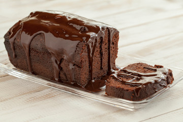 chocolate cake with slice and chocolate topping on a white tabl