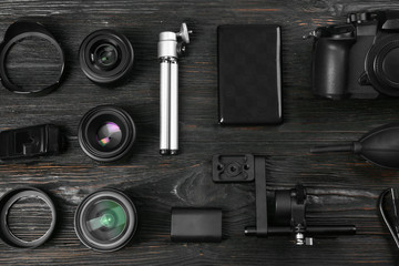 Flat lay composition with camera and video production equipment on black wooden table