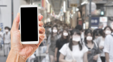 Blank black screen smartphone with abstract blur asian people wearing surgical face mask to prevent flu disease Coronavirus