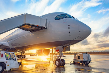 Airplane is parked with passengers in the evening at sunset with bright light.