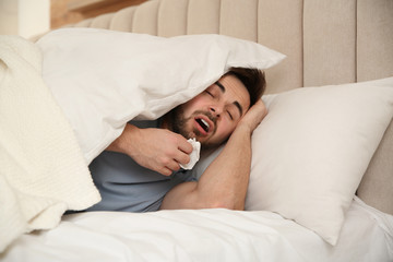 Sick young man in bed at home. Influenza virus