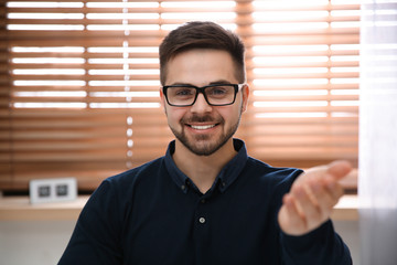 Happy man using video chat in modern office, view from web camera