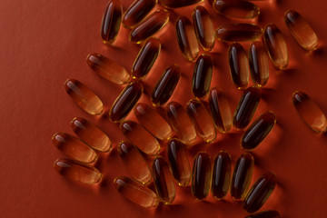 fish oil capsules on red background close-up