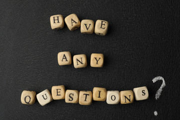 Phrase Have Any Questions made of wooden cubes on black background, flat lay