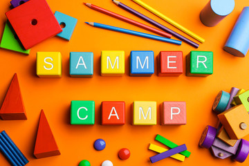 Colorful wooden cubes with phrase SUMMER CAMP on orange background, flat lay