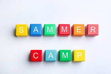 Obraz premium Colorful wooden cubes with phrase SUMMER CAMP on white background, top view