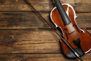 Fototapeta na wymiar Classic violin and bow on wooden background, top view. Space for text