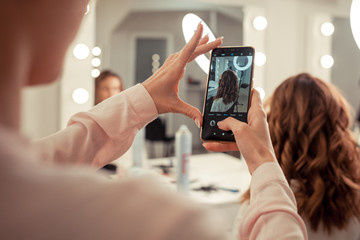The work of the stylist on hairstyles in a bright salon, the girl makes curls and a bunch of beautiful model