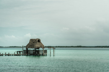 Bacalar lagoon at Quintana Roo, Yucatan Mexico. Pier and palapa on the lagoon. Beautiful thatched roof hut is in the middle of fresh water lake. Seven colors cenote is amazing and very rich on sulfur.