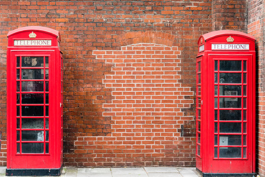 Two red Telephone Boxes against a brick wall, in London, landscape orientation. 