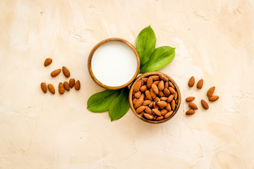 Obraz na płótnie Canvas Almond milk near nuts on beige background top-down