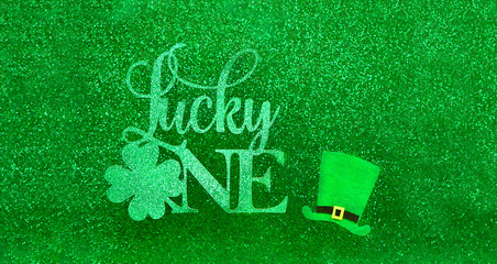 lucky one - text and traditional leprechaun hat on abstract shiny green background. St.Patrick`s...