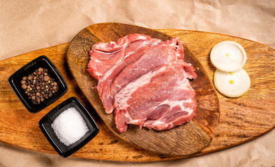top view. pork on wooden with onion, salt, pepper.