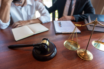 Lawyer working with client discussing contract papers with brass scale about legal legislation in...