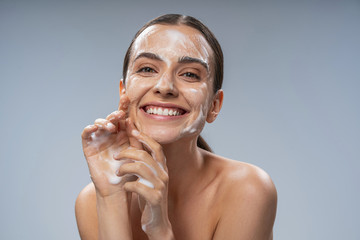 Happy Caucasian woman washing face with white soap