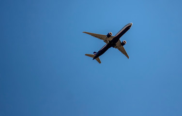 A plane leisurely flies through the blue sky