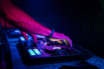 hands of a DJ mixing music on a professional controller in a booth