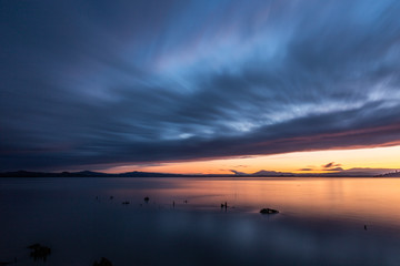Sunset a Trasimeno lake (Umbria, Italy), with fishing net poles and branches on perfectly still water