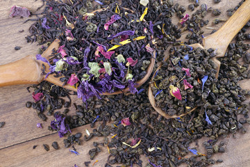 blended tea. black and green tea with dry flower petals and fruits. dry tea leaves in a wooden...