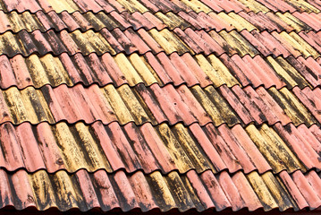 Old weathered roof tiles. close up of roof waved textures in red and yellow colors.  colored tiles form a pattern. Architecture background. Thailand house.