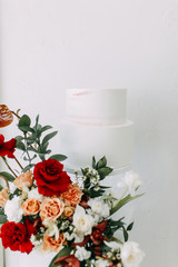 Multi-level cake with a decor of red roses. Wedding cake on a green background.