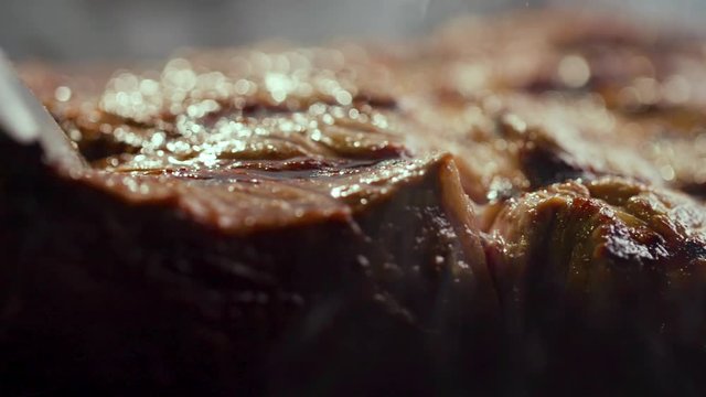 Chief using the tong and turning the meat on the grill. Fire is burning, hot juicy oil steak cooking close up slow motion. Grill, tasty beefsteak slow motion close up