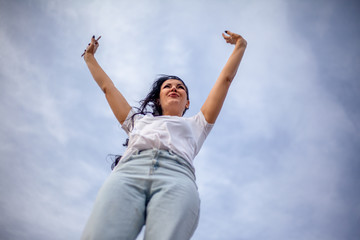 Happy woman with raised hands looking to the sky