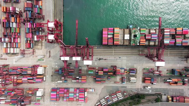 Large Container Ship docked at Hong Kong commercial port, top down aerial view including Stacks of Shipping containers on a holding platform.