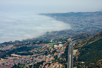 Fog steps on the city at the foot of the mountains