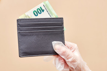100 Euro in a leather wallet. Hand of a detective in a glove holds money as evidence