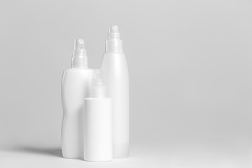 Set of cosmetic products in white and grey containers on light background.