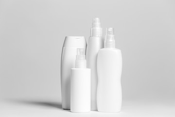 Set of cosmetic products in white and grey containers on light background.