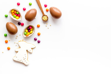 Easter sweets frame. Chocolate eggs and bunny gingerbread on white background top-down frame copy space