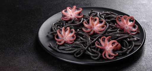 Black seafood pasta with shrimp, octopus and mussels on black background. Mediterranean gourmet food