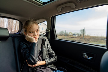 sad teen girl looks out window in seat back of car