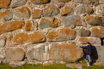 A girl stands on the background of stone wall of the Solovetsky monastery