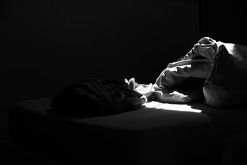 Untidy bed and sleeping cloths on the bed in black and white