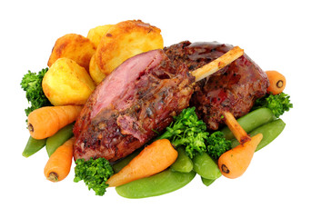 Slow cooked cured gammon shanks covered with caramelised maple sauce and roast potatoes, carrots, broccoli and sugar snap peas isolated on a white background
