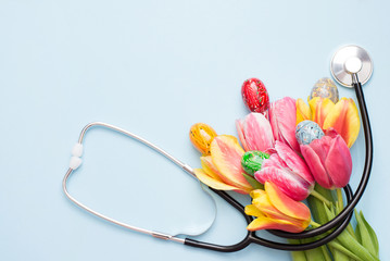 Eggs with stethoscope and flowers on blue background. copy space , medicine easter