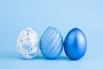 Chicken eggs painted in blue on a blue background. Creative card with Easter. Copy space